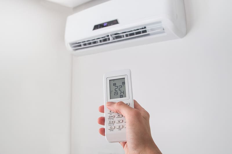 a person's hand holding a air conditioner controller